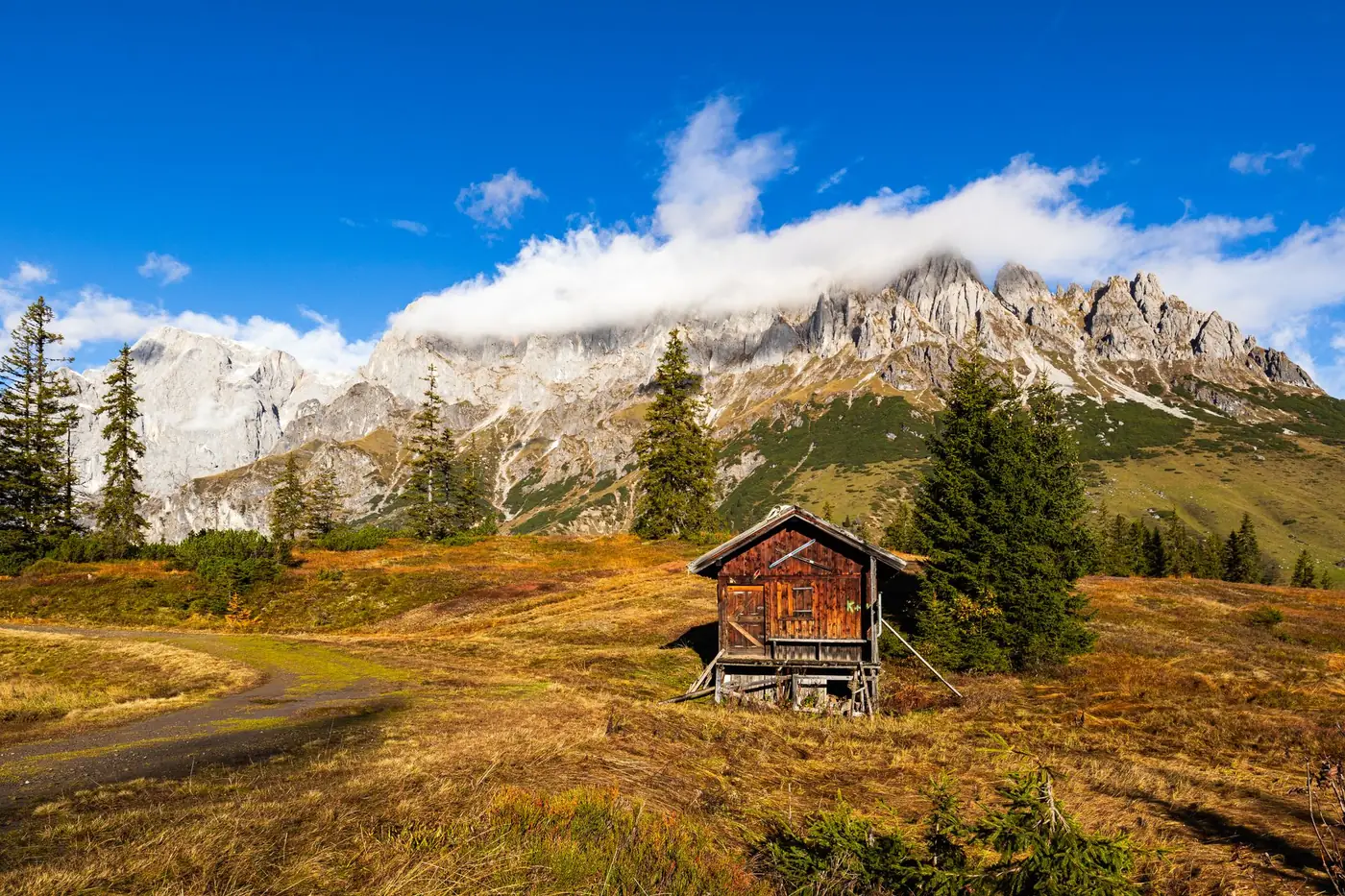 Houten berghut met uitzicht op een bergketen in de herfst