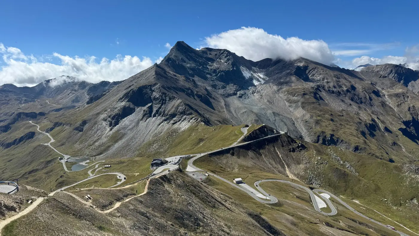 Bergweg met haarspeldbochten door een hooggebergte onder een blauwe lucht