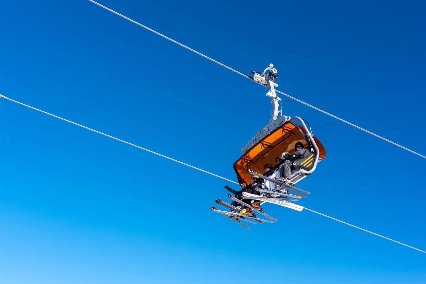 Skilift met skiërs tegen een blauwe hemel bij een skigebied