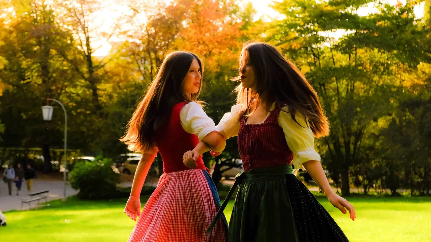 Twee vrouwen in traditionele Oostenrijkse klederdracht dansen buiten