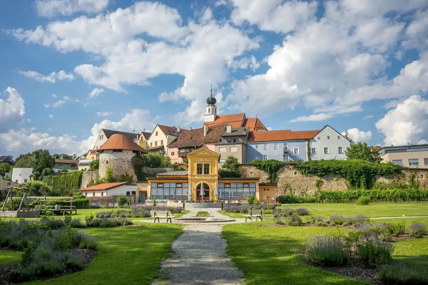 A picturesque view of Schärding's colorful townscape with lush gardens on a bright summer day.