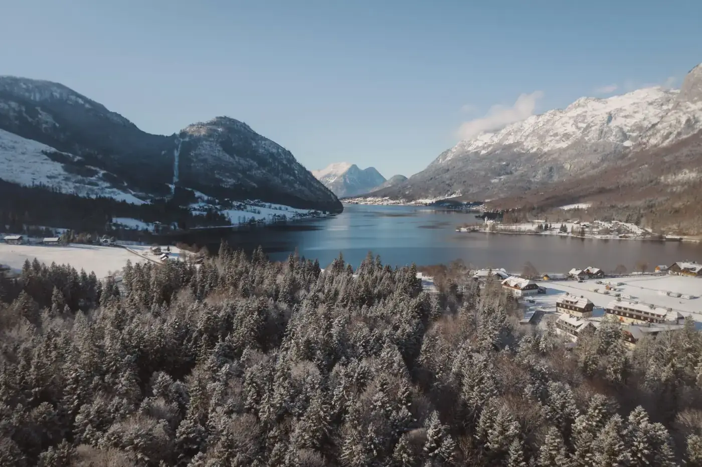 A breathtaking aerial view of a snow-covered village by a lake in the Austrian Alps.