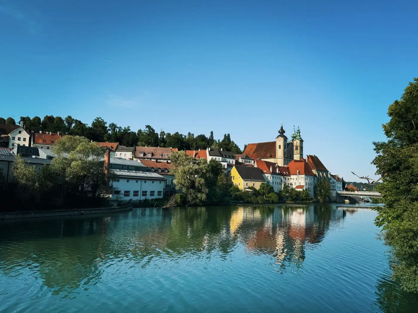 Beautiful daytime view of Steyr, Austria along the river with stunning reflections of historic buildings.