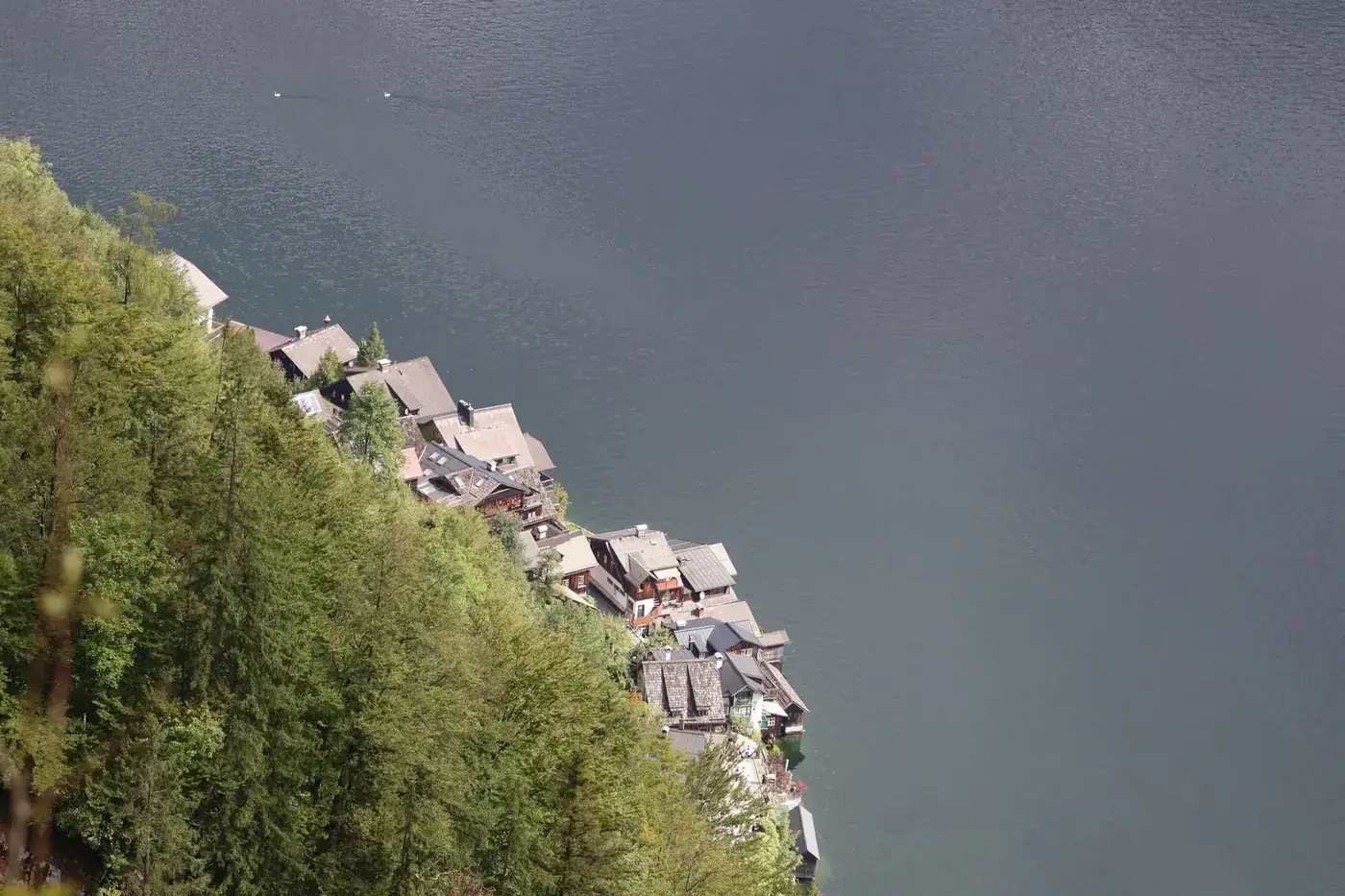 Scenic aerial view of a quaint village nestled by a tranquil lake surrounded by lush greenery.