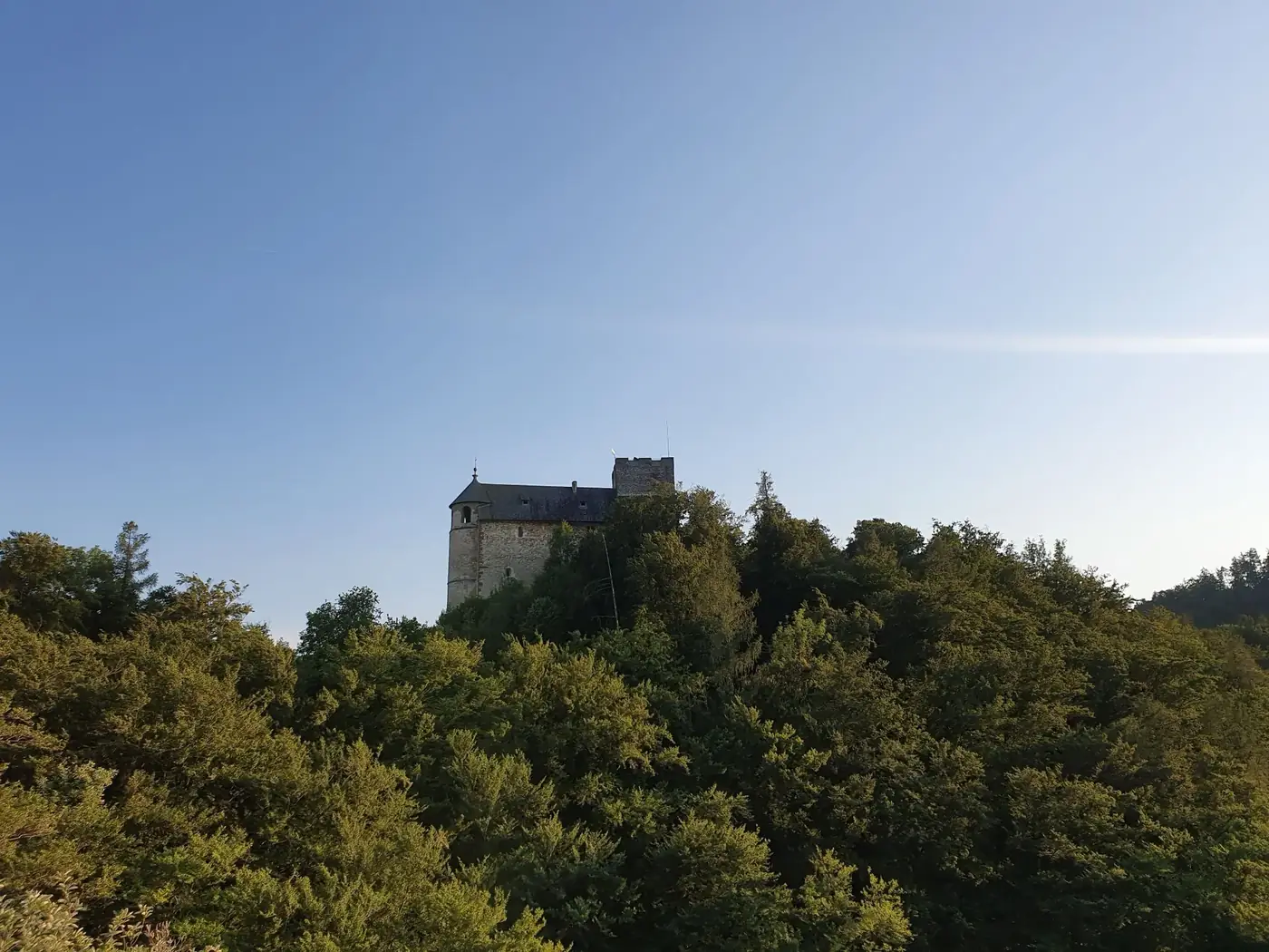 Gosting Castle stands amidst lush greenery under a clear blue sky.