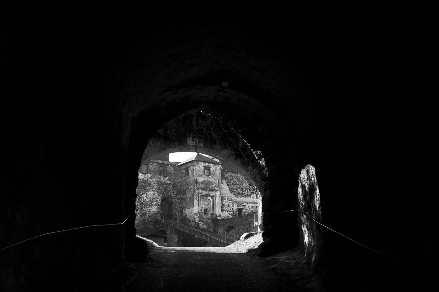Black and white view of Castle Güssing through a dark tunnel.
