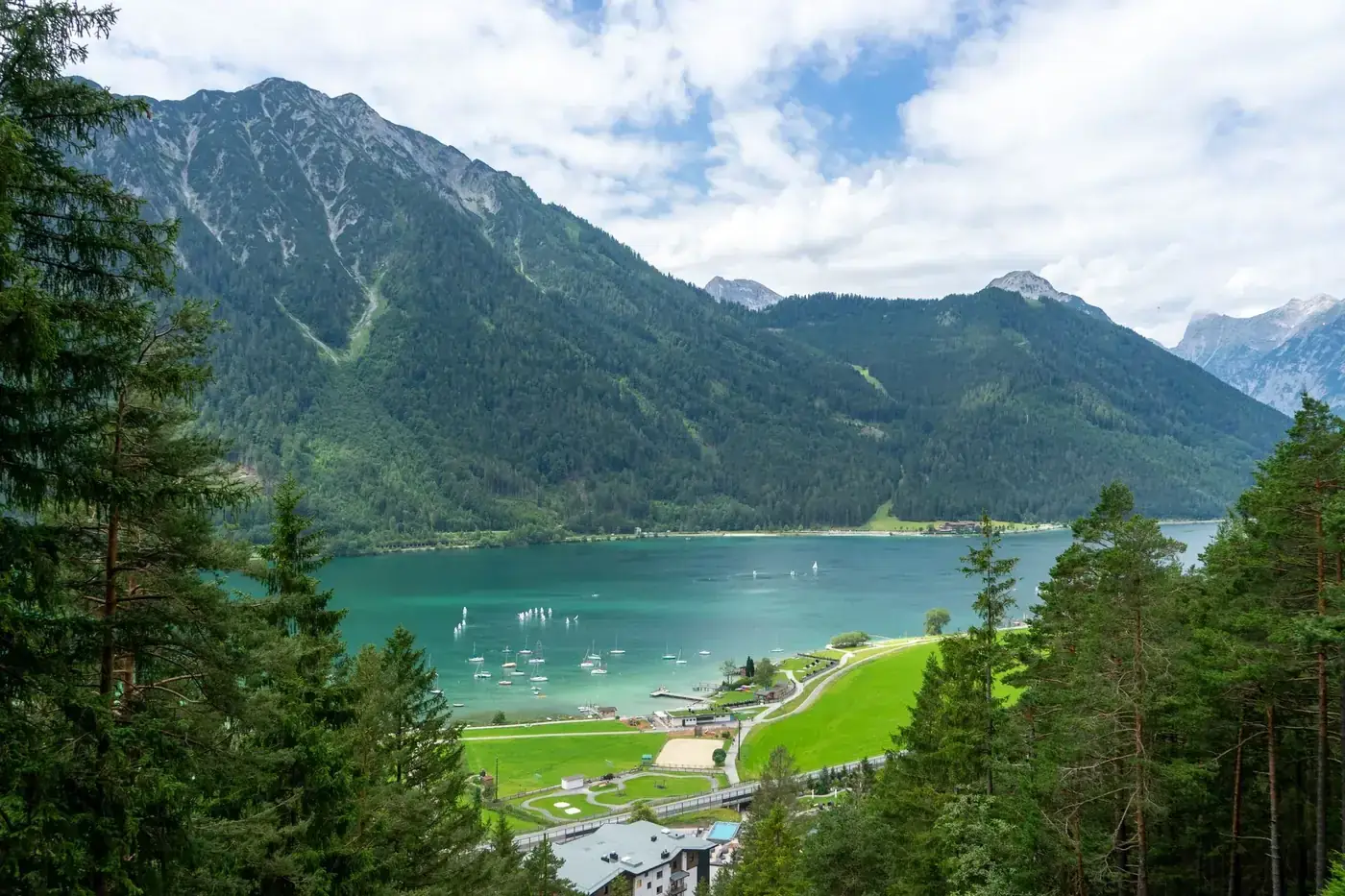 Breathtaking view of Achensee Lake with lush forests and mountain backdrop in Tyrol, Austria.
