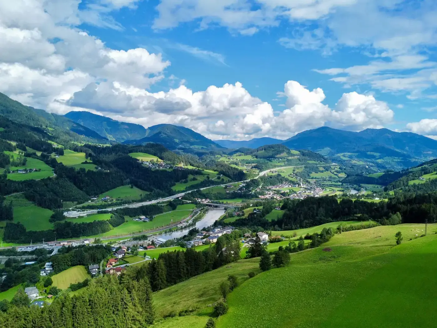 Breathtaking aerial shot of lush green valleys and mountains in the Austrian Alps.