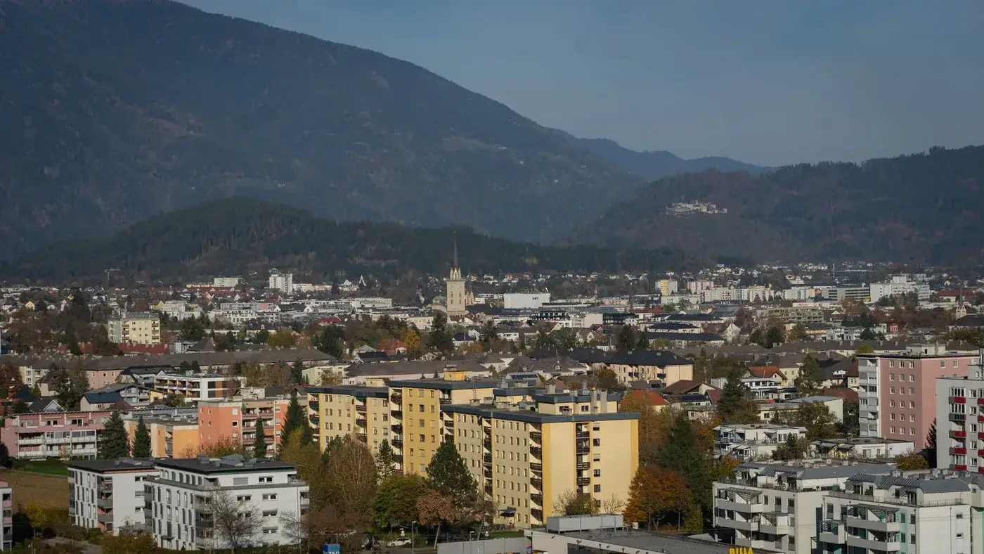 Aerial view of Villach showcasing urban landscape and mountains in autumn.