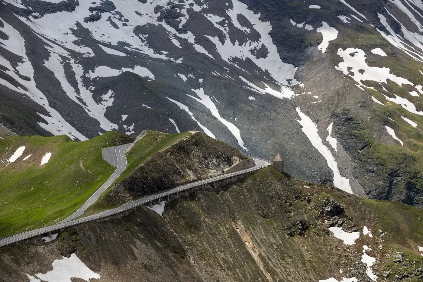 Aerial view of a winding alpine road through snow-covered mountains, perfect for travel imagery.