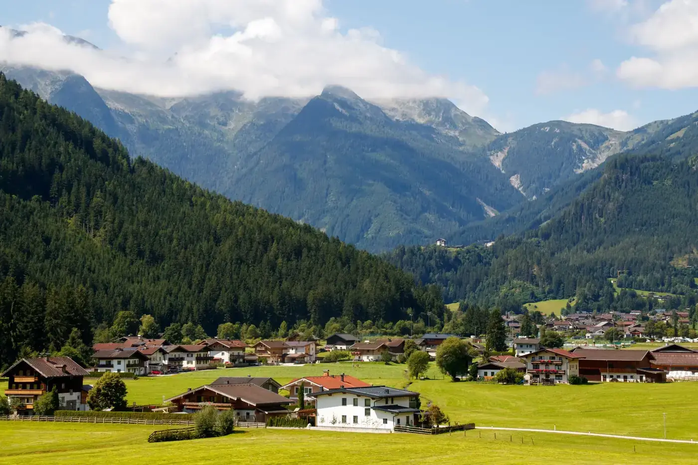 Charming alpine village nestled in lush green valley with towering mountains, ideal for travel.