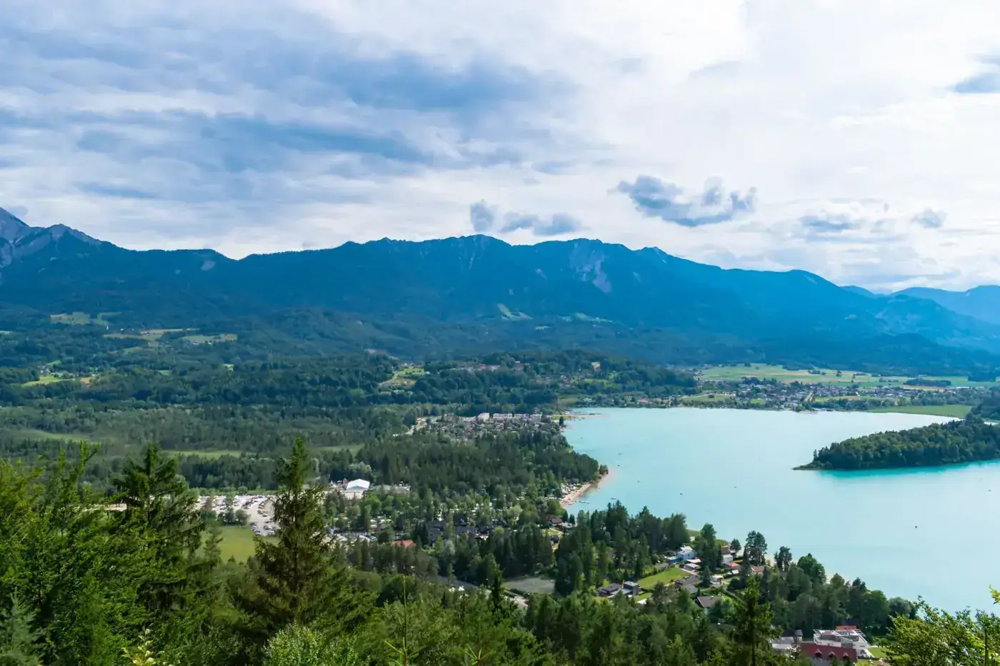 Serene landscape of Lake Faak and mountains with lush greenery in Austria.