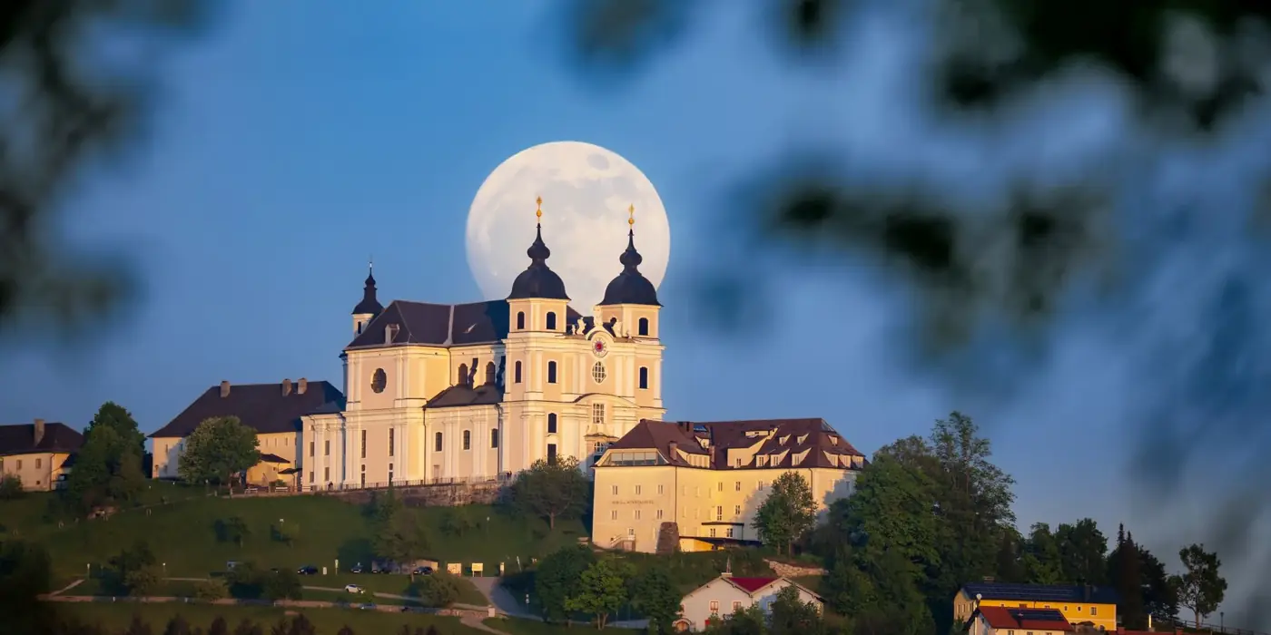 Stunning view of a Baroque church framed by a full moon, evoking a serene spring atmosphere.