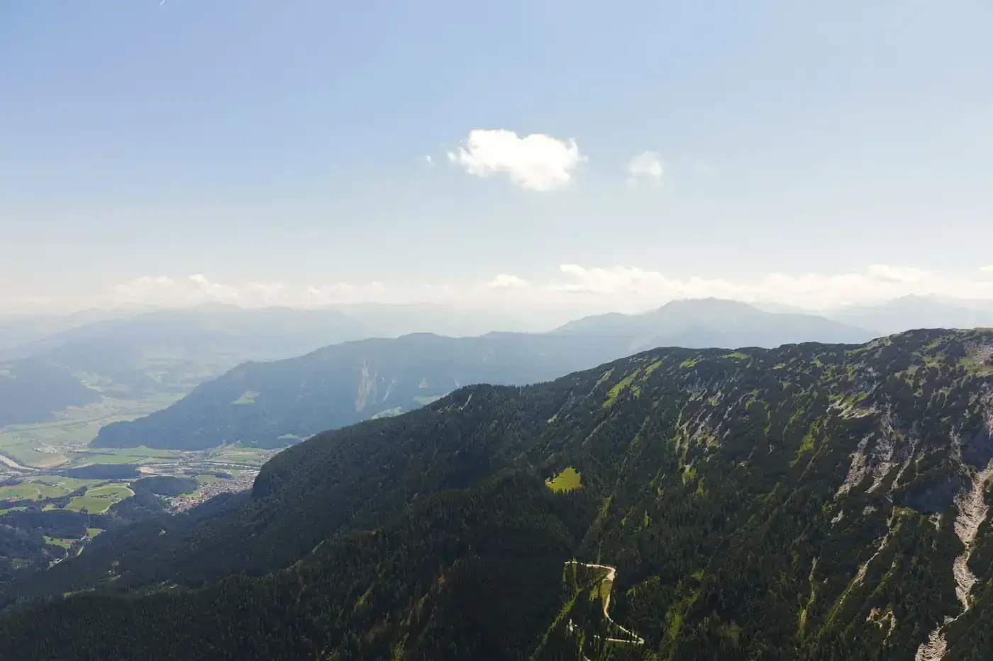 A stunning aerial view of the alpine landscape near Jenbach, Tyrol, Austria with lush vegetation and clear blue skies.