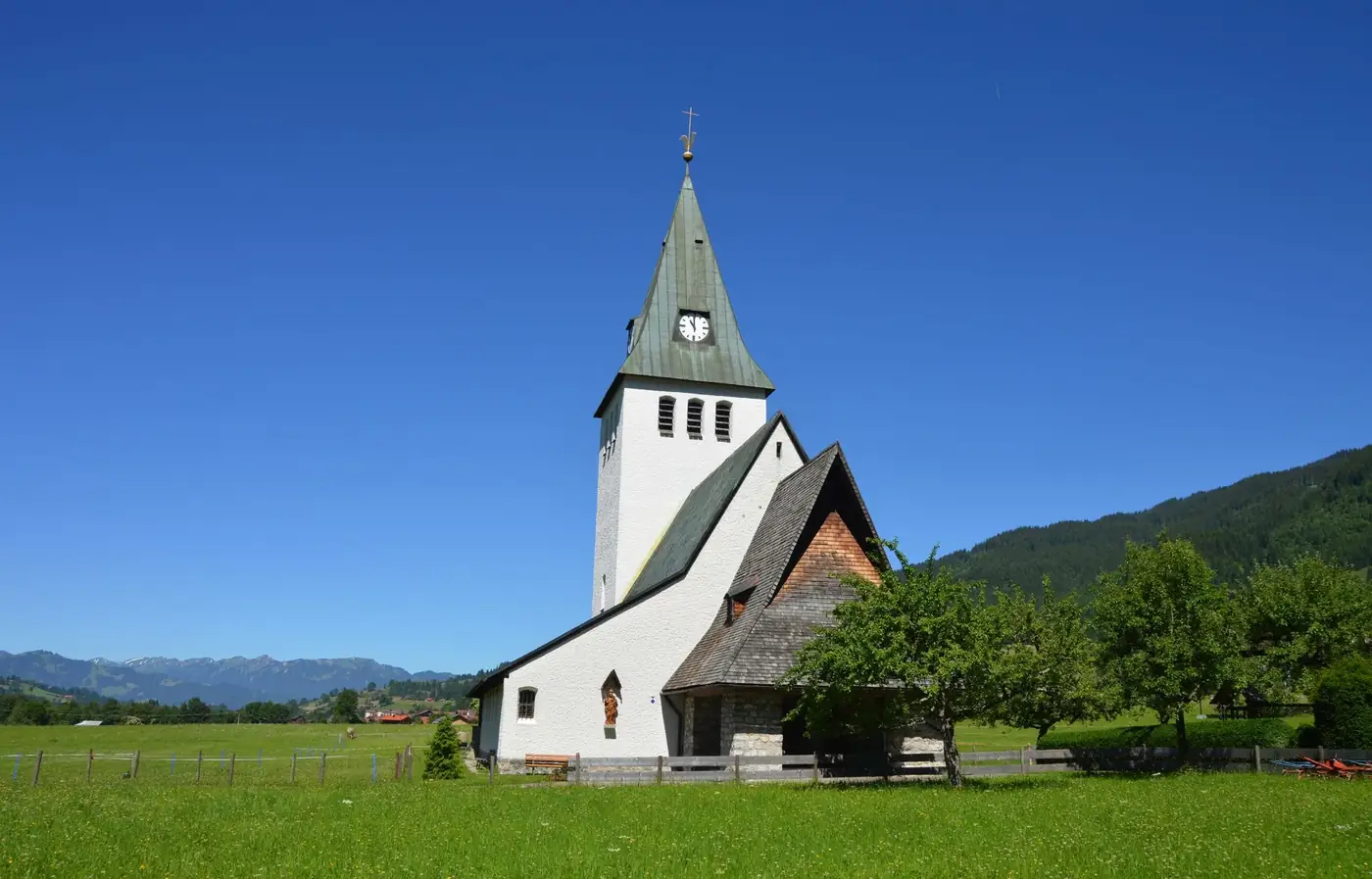 Picturesque rural church in green landscape under blue skies, embodying serene tranquility.