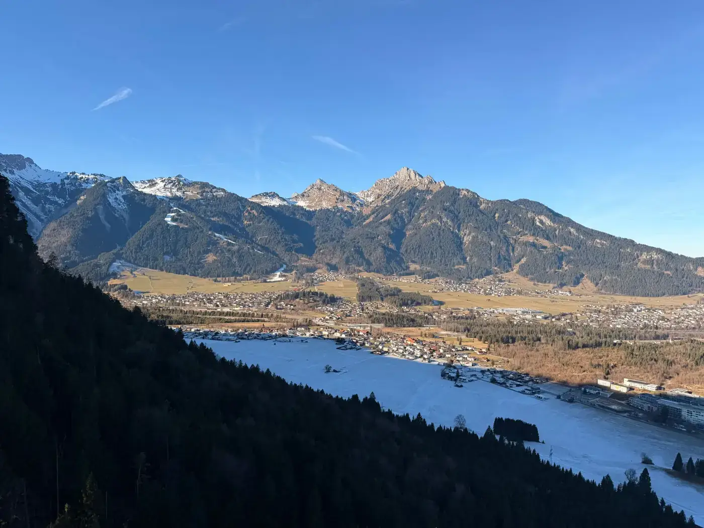 Panoramic view of snowy mountains and valley in Tirol, Austria, under clear blue skies.