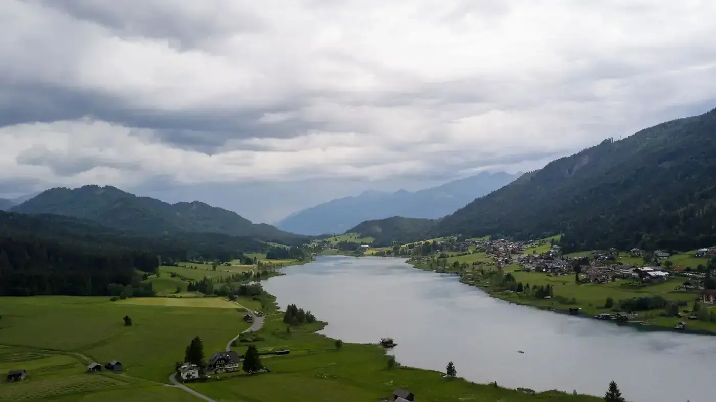 Cloudy day over Weißensee Lake, Kärnten, Austria, surrounded by mountains and lush greenery.