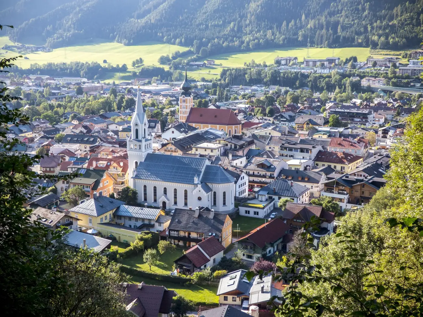 Stunning aerial view of a picturesque Alpine village nestled in lush surroundings featuring a prominent church.