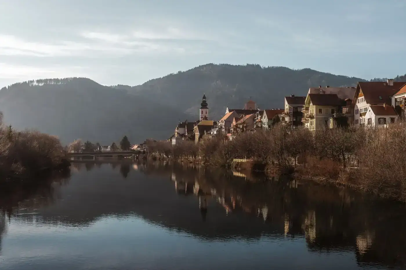 Idyllic view of Frohnleiten village reflecting on the river with mountainous backdrop.