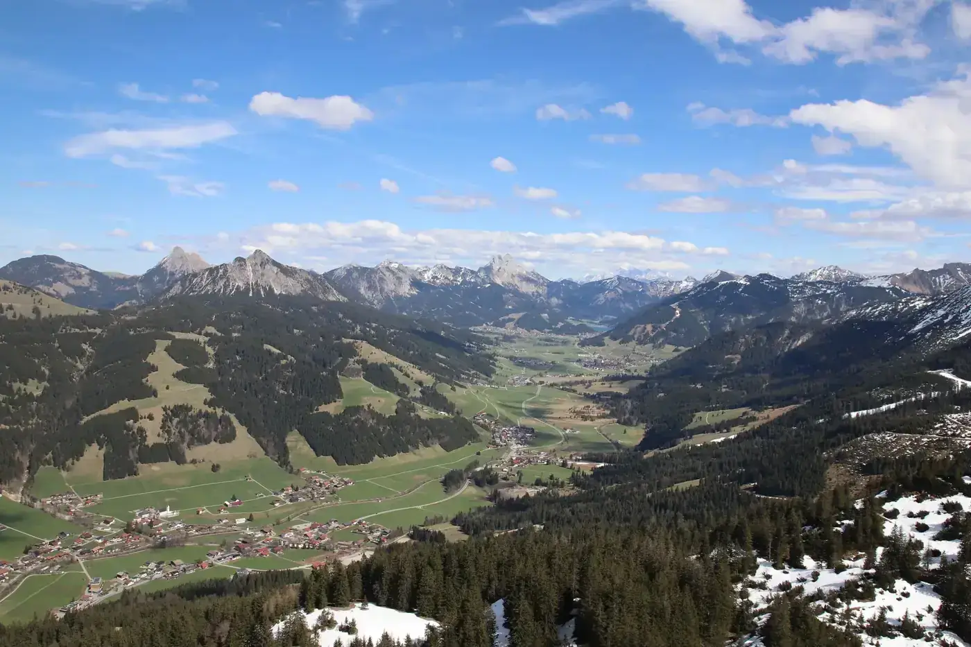 Panoramic view of the majestic Alps and valleys in Salzburg, Austria under a bright blue sky.