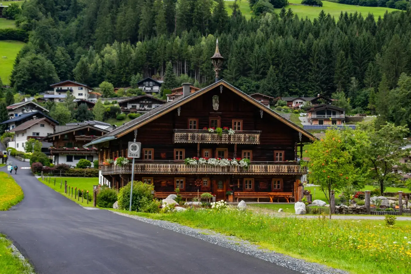 Picturesque alpine chalet surrounded by lush greenery in a European mountain village.