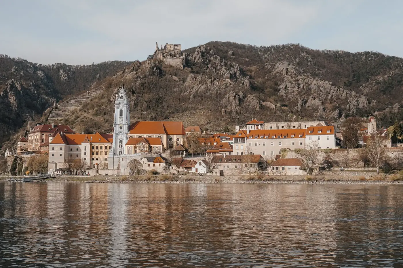 Picturesque view of Dürnstein Abbey on a hill by the Danube River surrounded by historic architecture.