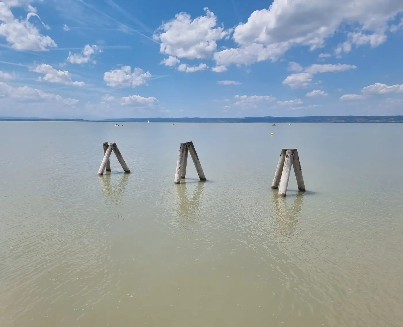 Peaceful scene of Lake Neusiedl with wooden posts and blue sky in Austria.