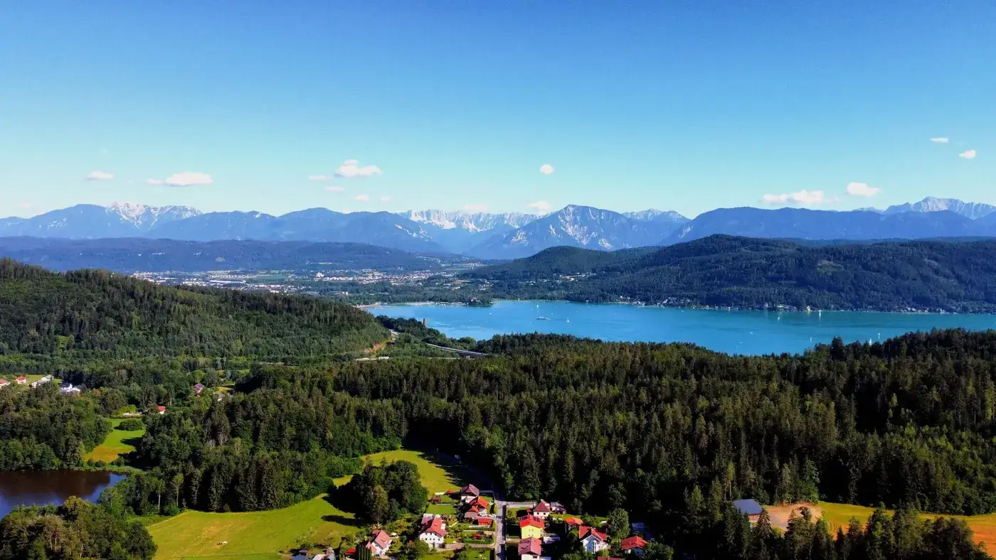 A breathtaking aerial view of Carinthia, Austria, showcasing lush forests, a scenic lake, and majestic mountains.