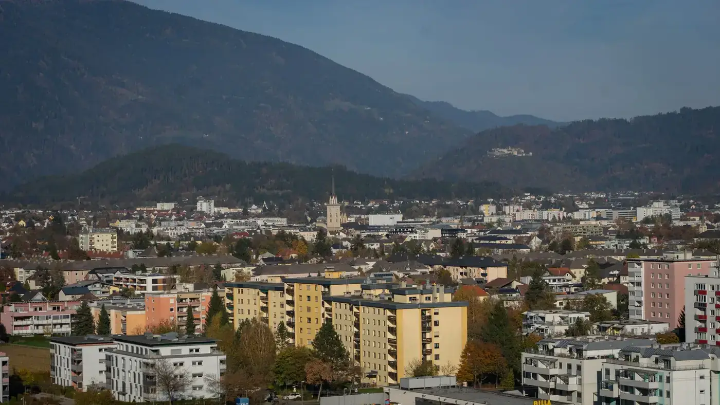Aerial view of Villach showcasing urban landscape and mountains in autumn.
