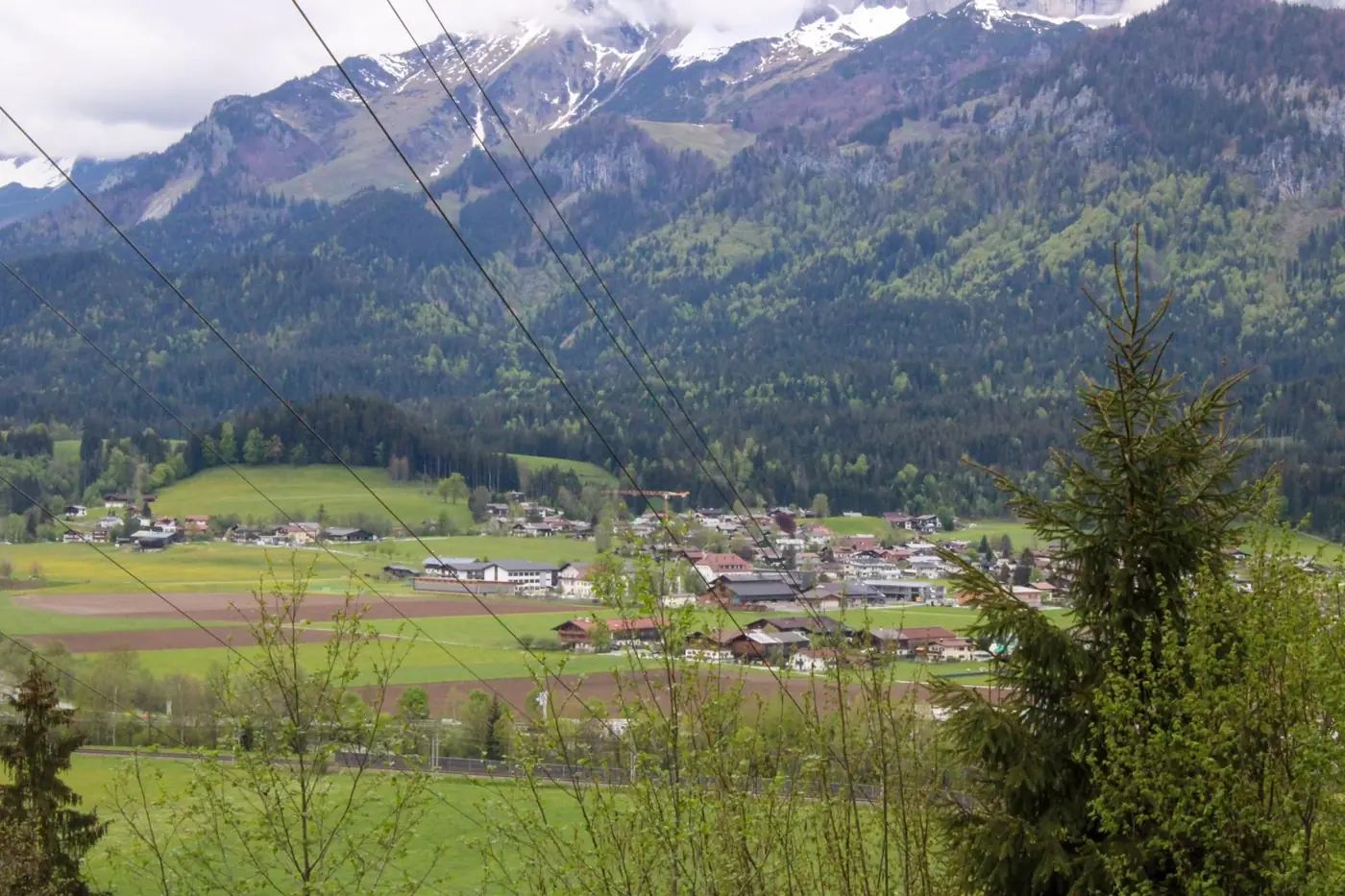 Explore the picturesque village of Sankt Johann in Tyrol, Austria, nestled amidst lush fields and majestic mountains.