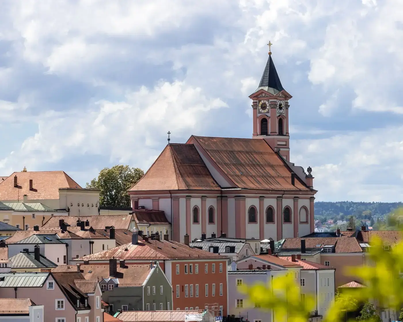 Beautiful architectural scene of a church in Passau, Germany with surrounding city rooftops under a cloudy sky.