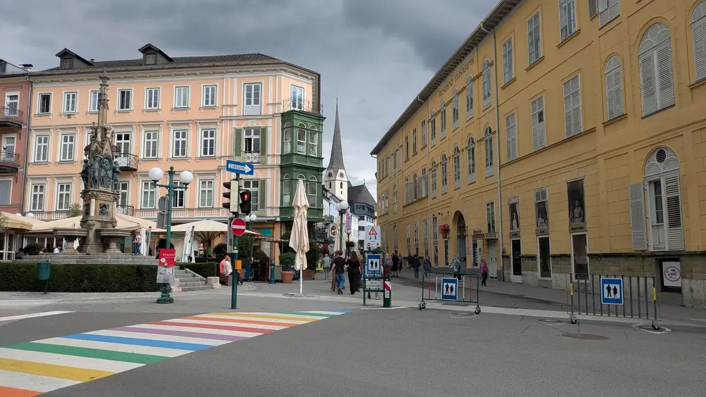 Vibrant town square with colorful crosswalk and historical buildings under a cloudy sky.