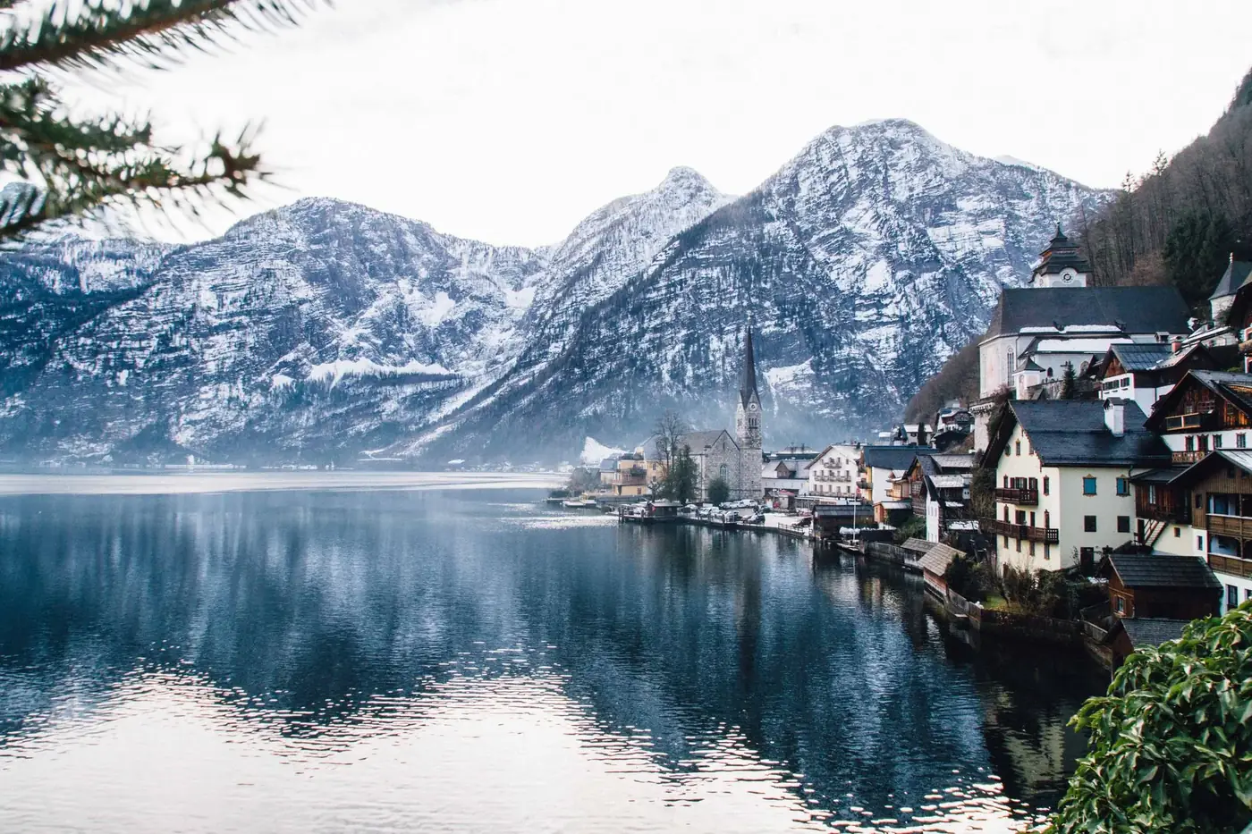 Scenic winter landscape of Hallstatt, Austria with snow-capped mountains and a tranquil lake.