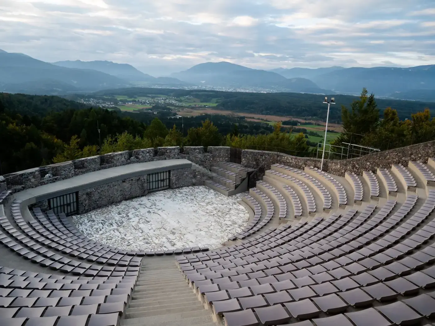 Scenic view of a historic amphitheater in Kärnten, Austria, with mountains in the background.